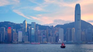 HONG KONG, ÇİN - 1 Mayıs 2018: Hong Kong gökdelenleri şehir merkezi gökdelenleri akşamları Victoria Limanı üzerinde hurda turist botlarıyla. Hong Kong, Çin