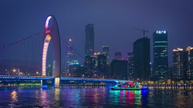 GuanGZHOU, ÇİN - 25 Mayıs 2018 Guangzhou şehir merkezi Pearl Nehri üzerindeki gökyüzü akşam panoramasında köprünün altından geçen turist botlarıyla aydınlatıldı. Guangzhou, Çin