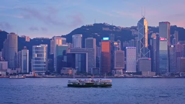 Hong Kong 2018年5月1日 香港のスカイラインは 観光ボートやフェリーで照らされた夕方にビクトリア港の上空の高層ビルを景色 カメラパン — ストック動画