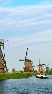 Hollanda 'nın ünlü Kinderdijk turistik bölgesinde turist botu ve yel değirmenleriyle Hollanda kırsalları. Kamera tavası