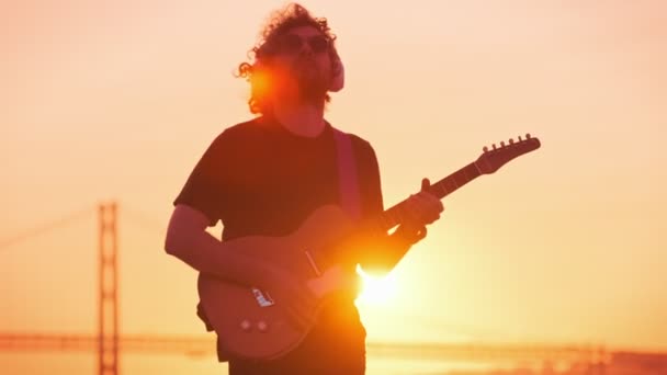 플레어와 가벼운 누출과 실루엣에 옥외에서 기타를 힙스터 음악가 — 비디오