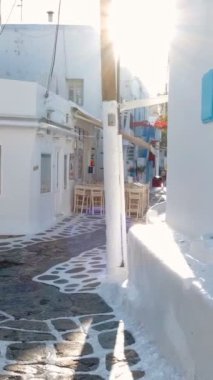 Yunanistan 'ın ünlü Mykonos adasında, Mykonos şehrinin mavi pencereli geleneksel beyaz boyalı evleri ve resimli manzaralı dar caddelerde sabit kameralı bir şekilde yürümek