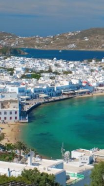 Meşhur yel değirmenleriyle Mykonos kasabası manzarası ve yaz günü tekneleri ve yolcu gemisi olan liman manzarası. Mykonos, Cyclades adaları, Yunanistan. Kamera tavasıyla