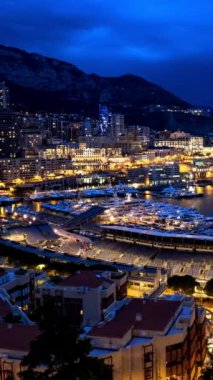 Monaco Monte Carlo marinası ve şehir silüeti zamanı. Monaco Limanı gece görüşü ve hızlı hareket eden bulutlar. Kamera tavası