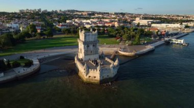 Belem Kulesi 'nin Tagus Nehri (Tejo) kıyısında günbatımında turist botuyla Lisboa' nın ünlü turizm merkezi ve turizm merkezinin insansız hava aracı görüntüsü. Lizbon, Portekiz. Yörünge paraşütü atışı