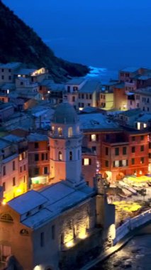 Cinque Terre Ulusal Parkı 'ndaki Vernazza köyünde kayalıklarda bulunan popüler turizm merkezleri akşam saatlerinde aydınlanan UNESCO Dünya Mirasları Sitesi, Vernazza, Liguria, İtalya. Kamera kaydıyla