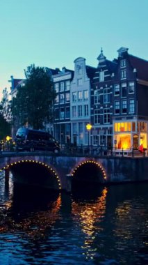 Amsterdam cityscape kanal, köprü ve ışıklı akşam alacakaranlık Ortaçağ evleri ile gece manzarası. Amsterdam, Hollanda