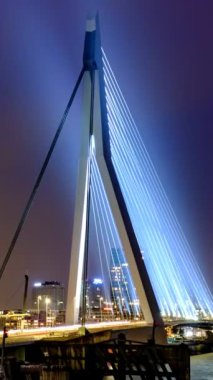 Gece, Nieuwe Maas üzerindeki Erasmus Köprüsü üzerindeki Rotterdam 'da sokak trafiğinin zamanlaması aydınlandı. Rotterdam, Hollanda. Kamera uzaklaşma efekti