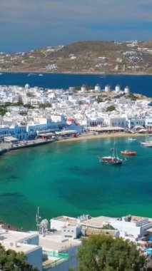 Meşhur yel değirmenleriyle Mykonos kasabası manzarası ve yaz günü tekneleri ve yolcu gemisi olan liman manzarası. Mykonos, Cyclades adaları, Yunanistan. Kamera tavasıyla