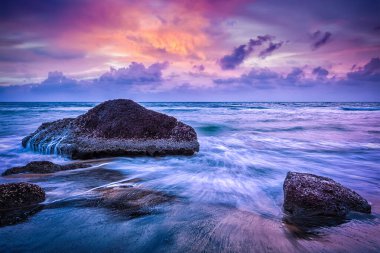 Tropik plaj tatili arka planı. Gün batımında dalgalar ve kayalar. Güzel bulutlu bir yer. Varkala, Hindistan