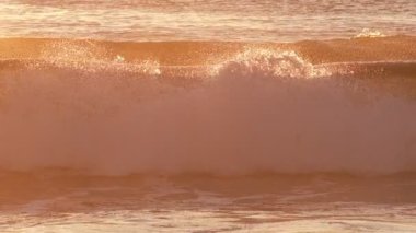 Gün batımında okyanus dalgalarını güneşe maruz bırakmak. Costa da Caparica, Portekiz. Yavaş çekim