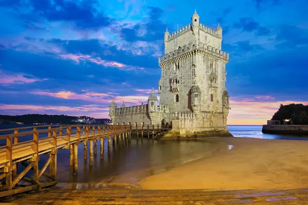 stock image Belem Tower or Tower of St Vincent - famous tourist landmark of Lisboa and tourism attraction - on the bank of the Tagus River (Tejo) after sunset in dusk twilight with dramatic sky. Lisbon, Portugal