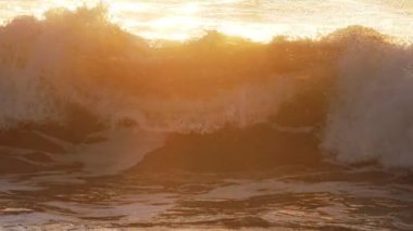 Gün batımında okyanus dalgalarını güneşe maruz bırakmak. Costa da Caparica, Portekiz. Yavaş çekim