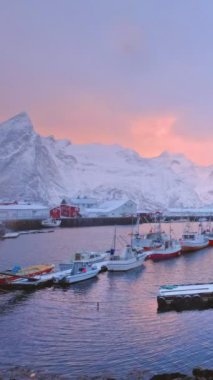 Norveç, Lofoten Adaları 'ndaki Hamnoy balıkçı köyünde gemileri olan rıhtım. Kış gündoğumunda kırmızı rorbu evleri ile birlikte. Yatay kamera tavası