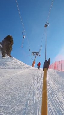 Kablolu sandalyede kayak kaldırmanın FPV bakış açısı Dolomitlerde alp kayağı için yükseliyor. İtalya 'da Dolomitler' de kayak yapan insanlarla kayak merkezi. Kayak alanı Belvedere. Canazei, İtalya