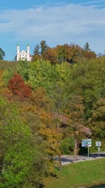 Kötü Tolz 'un ünlü turistik beldesinde sonbahar. Kalvarienbergkirche, Isar nehri, ağaçlar, Bavyera evleri ve Mary Varsayımı Kilisesi manzarası. Bad Toelz, Bavyera, Almanya. Yatay tava