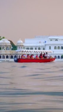 Udaipur Gölü Sarayı 'nın ünlü lüksü Jaguar Nivalar gün batımında Pichola Gölü' nde Rajput mimarisi Rajasthan 'ın Mewar Hanedanı' nın hükümdarları. Turist botu yan tarafa gidiyor. Udaipur, Hindistan