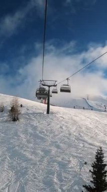 Kablolu sandalyede kayak kaldırmanın FPV bakış açısı Dolomitlerde alp kayağı için yükseliyor. İtalya 'da Dolomitler' de kayak yapan insanlarla kayak merkezi. Kayak alanı Belvedere. Canazei, İtalya