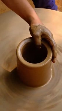 Çömlekçinin becerikli ıslak elleri çömlekçi çarkındaki killeri şekillendiriyor ve vazo yontuyor. Geleneksel el yapımı Hint kasesi, kavanoz, esrar, sürahi üretiyor. Shilpagram, Udaipur, Rajasthan, Hindistan