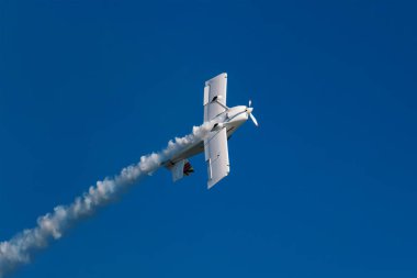 Ters uçuşta dublör akrobatik uçak mavi gökyüzünde dumanla dublörlük yapıyor. Hız kavramı, zorluk, kesinlik, risk, meydan okuma