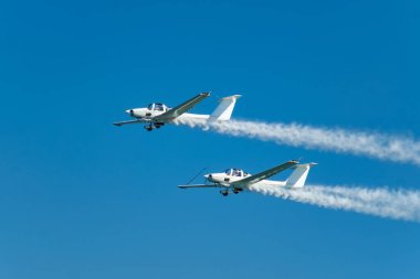 Dublör akrobatik uçak dumanla mavi gökyüzünde gösteri yapıyor. Takım çalışması, işbirliği, koordinasyon, güven, hassasiyet, zorluk, zorluk, hız, sinerji kavramı