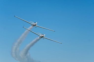 Dublör akrobatik uçak dumanla mavi gökyüzünde gösteri yapıyor. Takım çalışması, işbirliği, koordinasyon, güven, hassasiyet, zorluk, zorluk, hız, sinerji kavramı
