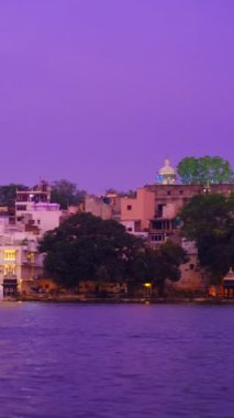 Ünlü lüks Udaipur Şehir Sarayı, Lal ghat, Pichola Gölü kıyısında evler günbatımında su dalgalarıyla aydınlandı - Mewars 'ın Rajput mimarisi. Udaipur, Rajasthan, Hindistan. Yatay tava