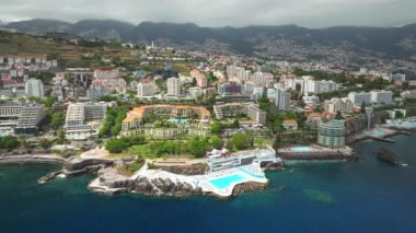 Funchal şehrinin havadan insansız hava aracı görüntüsü. Oteller, oteller ve Atlantik Okyanusu kıyısında yüzme havuzu. Funchal, Madeira, Portekiz. Dolly hareketine yaklaş.