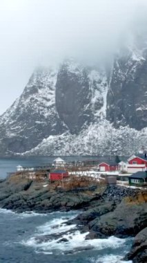 Norveç, Lofoten Adaları 'ndaki meşhur geleneksel balıkçı köyü Hamnoy' da kışın karlı kırmızı rorbu evleri
