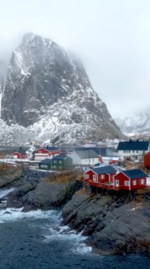 Norveç, Lofoten Adaları 'ndaki meşhur geleneksel balıkçı köyü Hamnoy' da kırmızı rorbu evleri var. Kışın kar yağarken