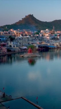 Hindistanın ünlü Hinduizm hac kasabası kutsal Hindu dini şehri Puşkar Brahma mandir tapınağı, göl ve günbatımında geleneksel ghatları olan tepelerin arasında. Rajasthan, Hindistan. Yatay tava