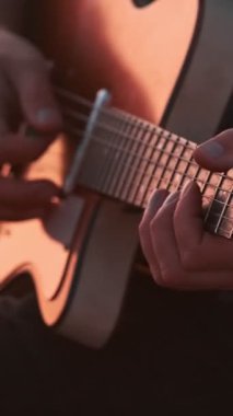 Sokak müzisyeni gitar çalarken arka planda suyla birlikte yakın çekim yapıyor.
