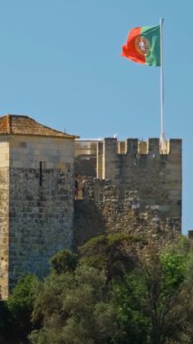 Portekiz Lisboa 'daki Saint George Kalesi Castelo de Sao Jorge. Yürüyen turistler ve büyük Portekiz bayrağı.