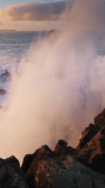 Cabo Carvoeiro, Peniche, Portekiz 'de günbatımında okyanus kıyısındaki kayalık dalgalarla çarpışıyor.