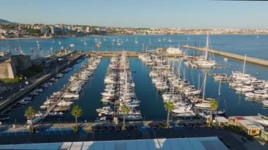 Günbatımında Cascais Kalesi, Portekiz 'de demirli yat tekneleriyle Cascais marinasının hava manzarası. Dolly hareketine yaklaş.
