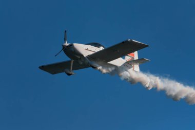 Dublör akrobatik uçak dumanla mavi gökyüzünde gösteri yapıyor. Hız kavramı, zorluk, kesinlik, risk, meydan okuma