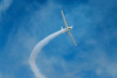 Dublör akrobatik uçak mavi gökyüzünde dumanla döngü yapıyor. Hız kavramı, zorluk, kesinlik, risk, meydan okuma