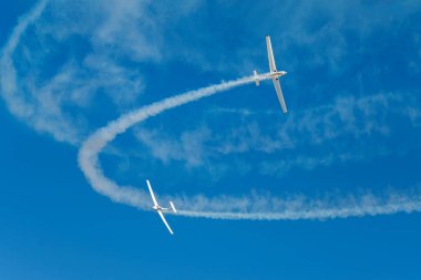 Dublör akrobatik uçak dumanla mavi gökyüzünde gösteri yapıyor. Takım çalışması, işbirliği, koordinasyon, güven, hassasiyet, zorluk, zorluk, hız, sinerji kavramı