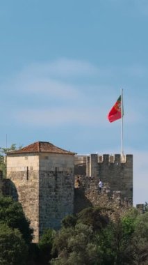 Portekiz Lisboa 'daki Saint George Kalesi Castelo de Sao Jorge. Yürüyen turistler ve büyük Portekiz bayrağı.