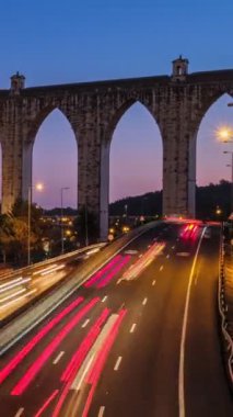 Campolide İstasyonu yakınlarındaki otoyol trafiğinin zaman aşımına uğraması ve arka planda Aguas Livres Aqueduct ile birlikte gece araba ışıkları izleri. Lizbon, Portekiz. Kamera tavası