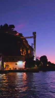 25 de Abril Köprüsü 'nün Tagus Nehri ve Boca do Vento Asansörü üzerindeki Lizbon' un ünlü turistik beldesi ve akşamları insanlarla birlikte deniz kenarındaki restoranların manzarası. Lizbon, Portekiz