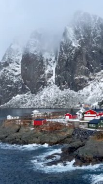 Norveç, Lofoten Adaları 'ndaki meşhur geleneksel balıkçı köyü Hamnoy' da kırmızı rorbu evleri var. Kışın kar yağarken. Kamera tavası