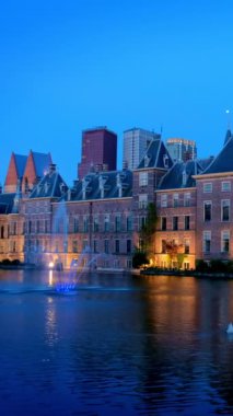 Binnenhof Parlamentosu ve Hofvijver Gölü manzarası. Arka planda gökdelenler gece aydınlandı. Lahey, Hollanda 'da. Kamera tavası