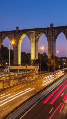 Campolide İstasyonu yakınlarındaki karayolu trafiğinin zaman aşımına uğraması ve arka planda Aguas Livres Aqueduct ile birlikte araba ışıkları izleri. Lizbon, Portekiz. Etkin büyüt