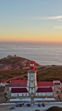 Cabo Espichel Cape Espichel 'deki deniz fenerinin hava aracı görüntüsü Atlantik Okyanusu' nda gün batımında. Sesimbra, Portekiz. Yörünge paraşütü atışı