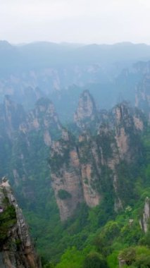 Çin 'in ünlü turistik merkezi - Zhangjiajie taş sütunları Wulingyuan, Hunan, Çin' deki sis bulutlarında uçurum tepeleri. Kamera tavası