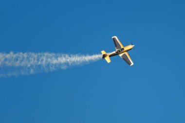 Altın dublör akrobatik uçak mavi gökyüzünde dumanla gösteri yapıyor. Hız kavramı, zorluk, kesinlik, risk