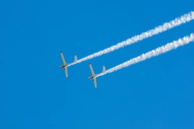 Dublör akrobatik uçak dumanla mavi gökyüzünde gösteri yapıyor. Takım çalışması, işbirliği, koordinasyon, güven, hassasiyet, zorluk, zorluk, hız, sinerji kavramı