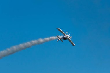 Dublör akrobatik uçak dumanla mavi gökyüzünde gösteri yapıyor. Hız kavramı, zorluk, kesinlik, risk, meydan okuma