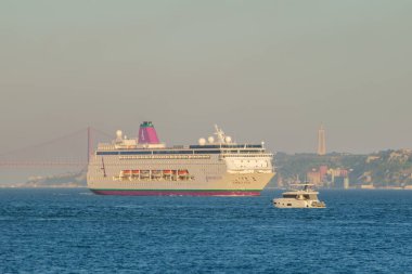 Oeiras, Portekiz - 30 Eylül 2023: Tejo Nehri 'ndeki ihtiraslı yolcu gemisi 25 Nisan köprüsü ve arka planda Cristo Rei heykeliyle Lizbon' dan ayrılıyor